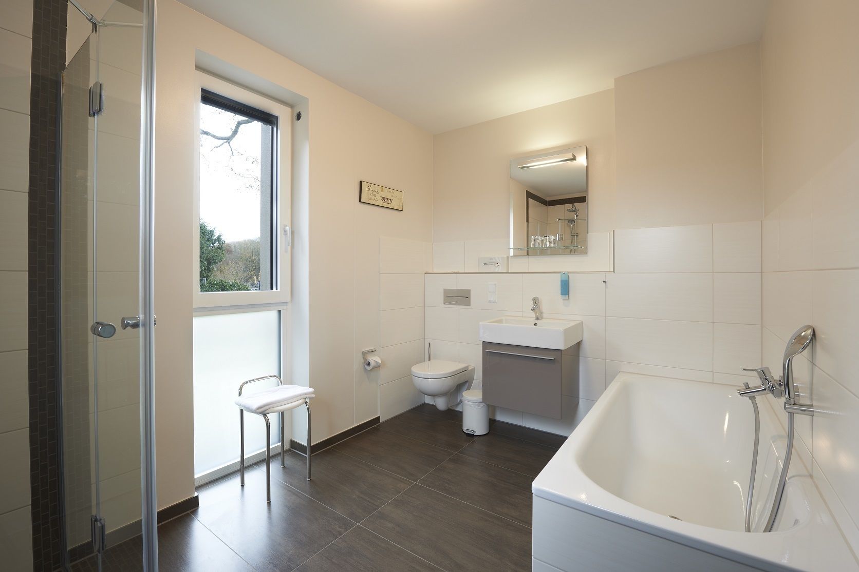 A modern bathroom with a shower, toilet, sink, and bathtub.