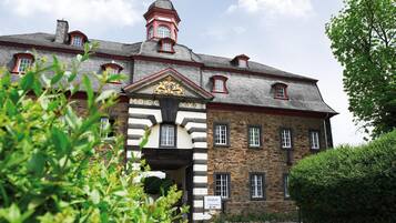 A historic building with a prominent entrance, stone walls, and a tower with a red roof.
