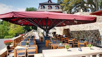An outdoor dining area with stone walls and a wooden table and chairs arrangement.