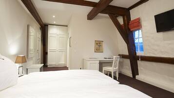 Een slaapkamer met een groot bed, een bureau, een stoel, een aan de muur bevestigde televisie en een raam met uitzicht.