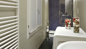 A narrow bathroom with a white radiator, a white sink, and a blue tiled shower area. - Rialto Al Manganer (Venice)