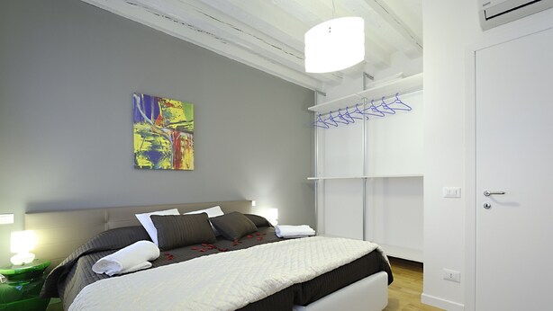 A modern bedroom with a bed, a painting, a wardrobe, and a hanging rack. - Rialto Al Manganer (Venice)