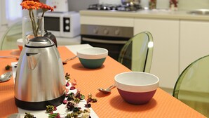 A kitchen with a microwave, stove, and a table with a bowl and a thermos. - Rialto Al Manganer (Venice)