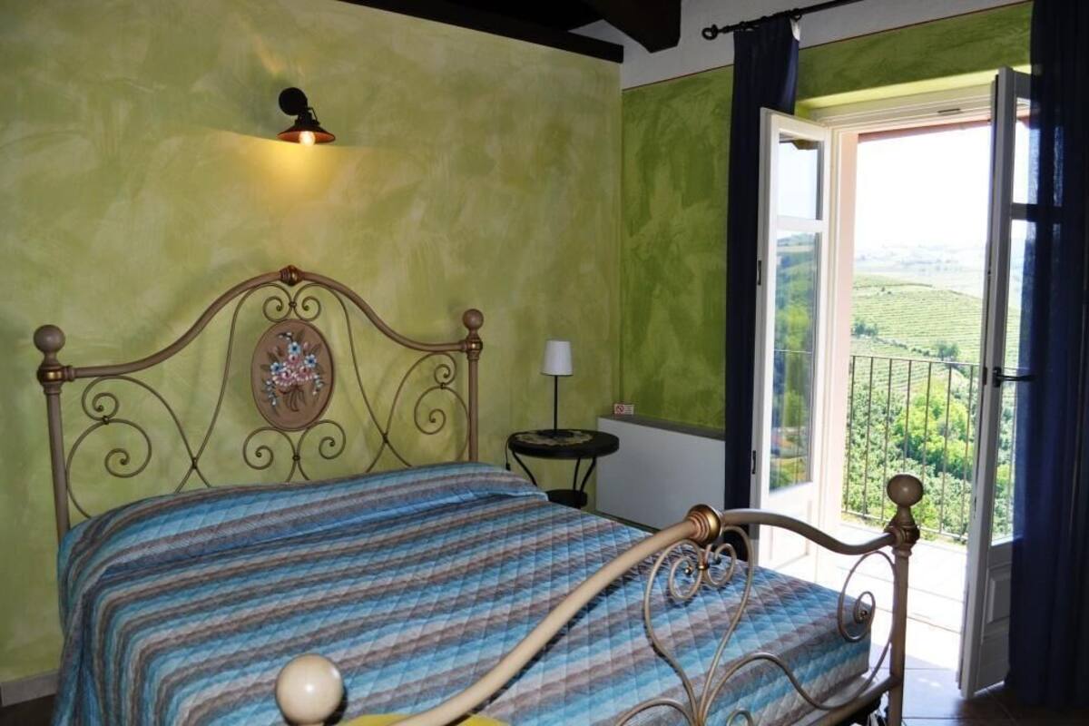 Une pièce comprenant un lit, une petite table, une lampe et une fenêtre donnant sur un paysage verdoyant.