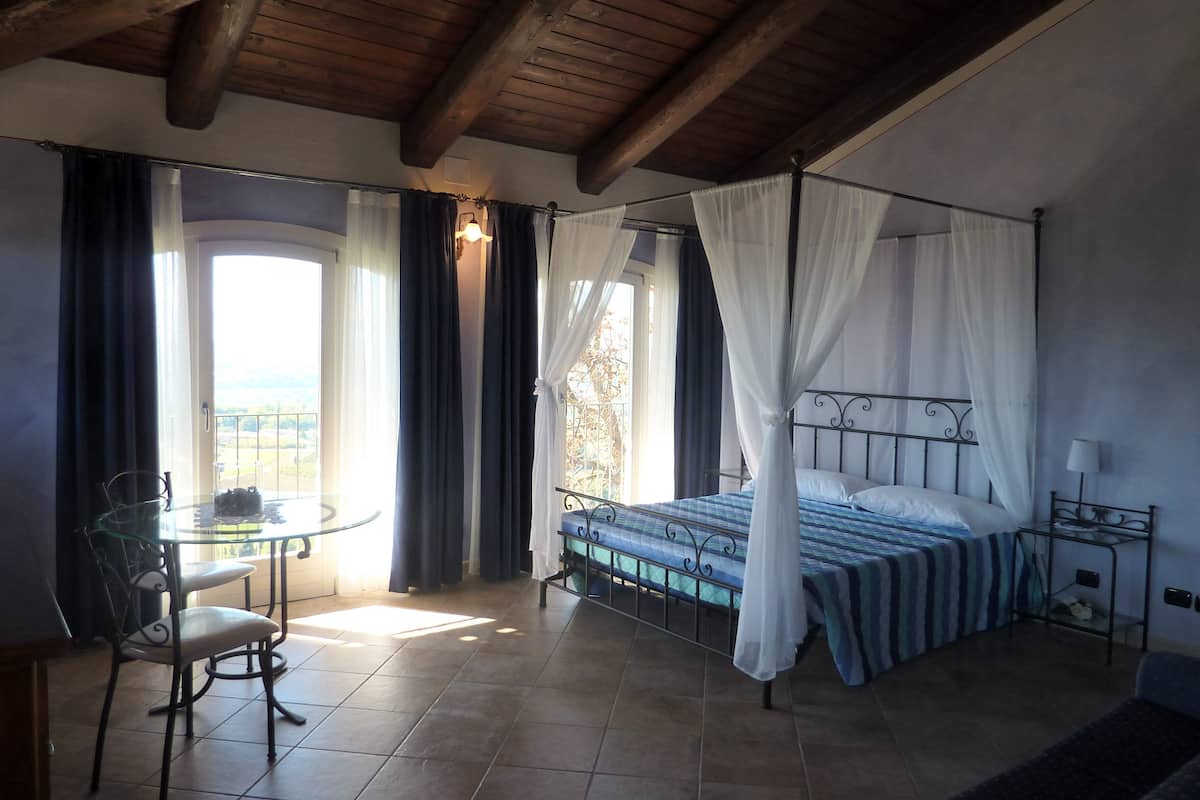 Une chambre à coucher avec un lit à baldaquin, une table en verre et une chaise.