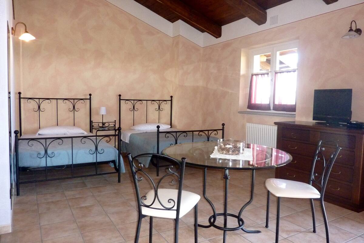 Une chambre avec deux lits, une table à manger avec des chaises, une commode et un téléviseur.
