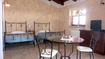 A bedroom with two beds, a dining table with chairs, a dresser, and a television.