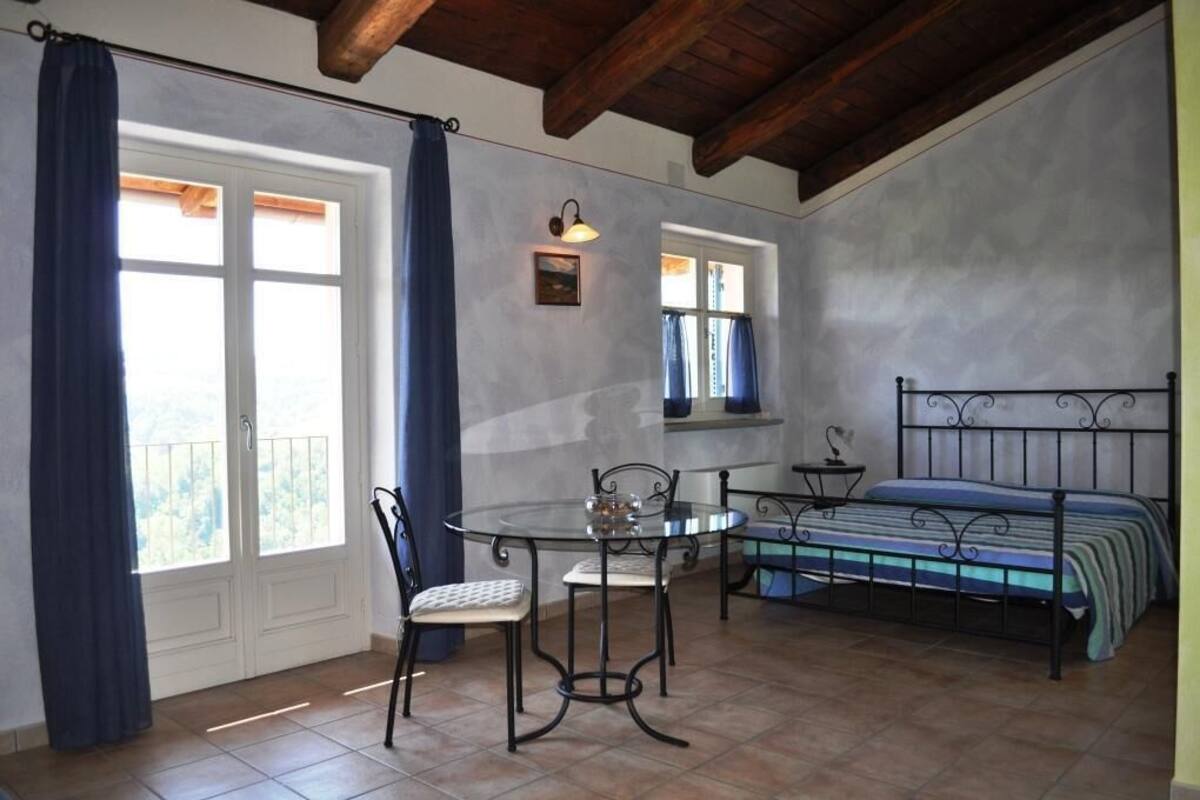 Une pièce avec un lit, une table et des chaises, et une fenêtre avec des rideaux.