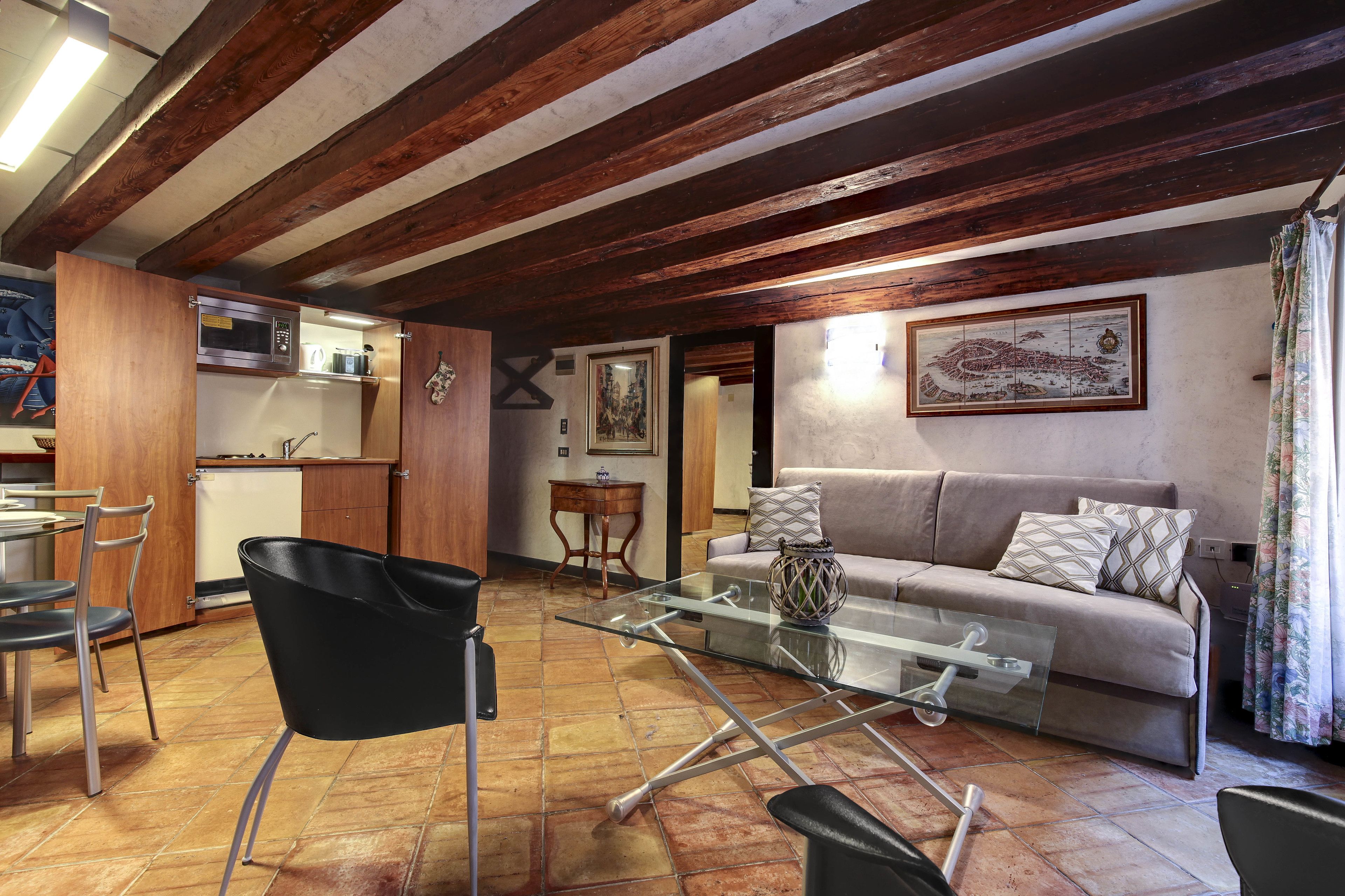 Una sala de estar con una mesa de centro de vidrio, un sofá y un comedor con sillas y una mesa.