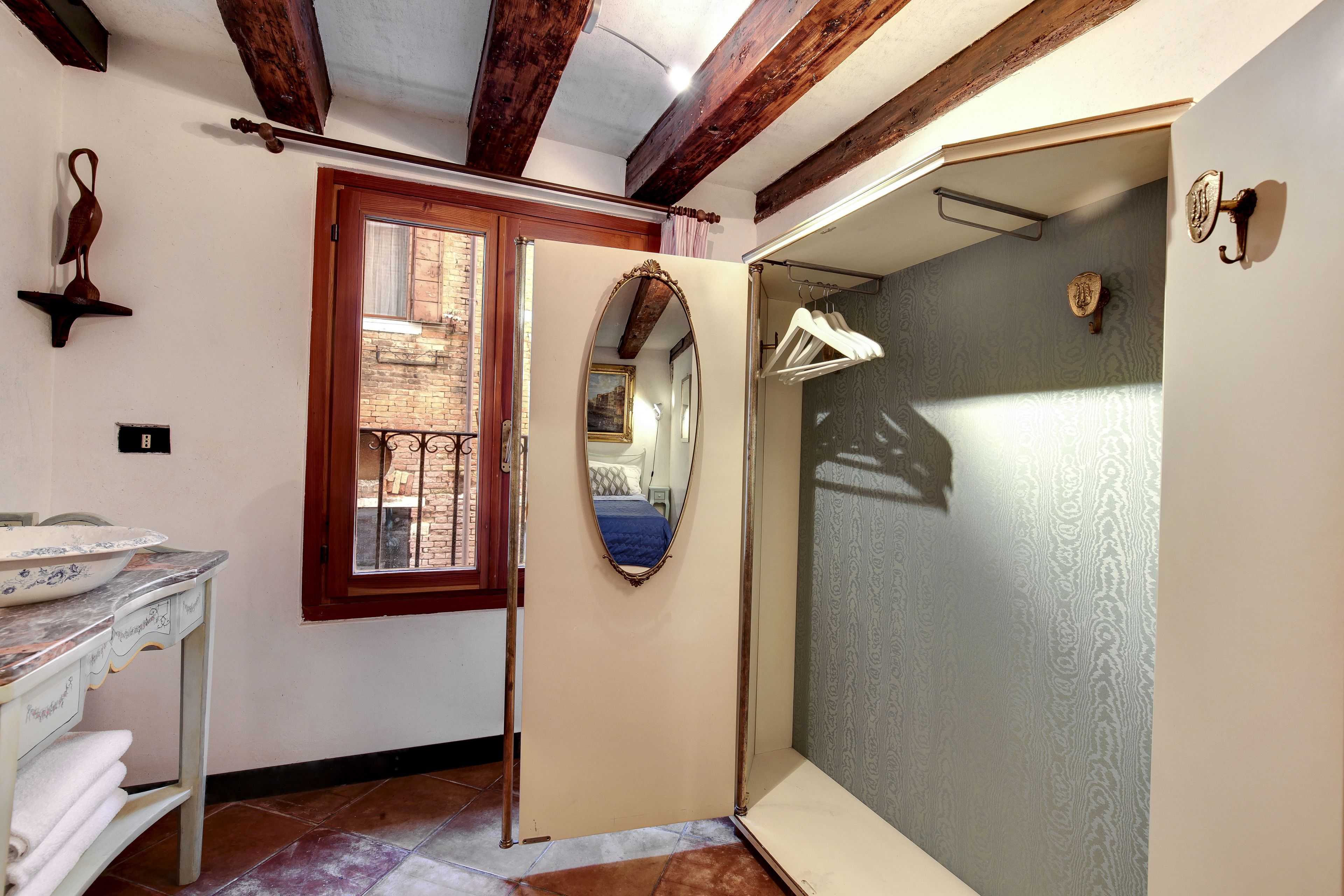 A room with a wooden ceiling, a mirror, a door, and a window.