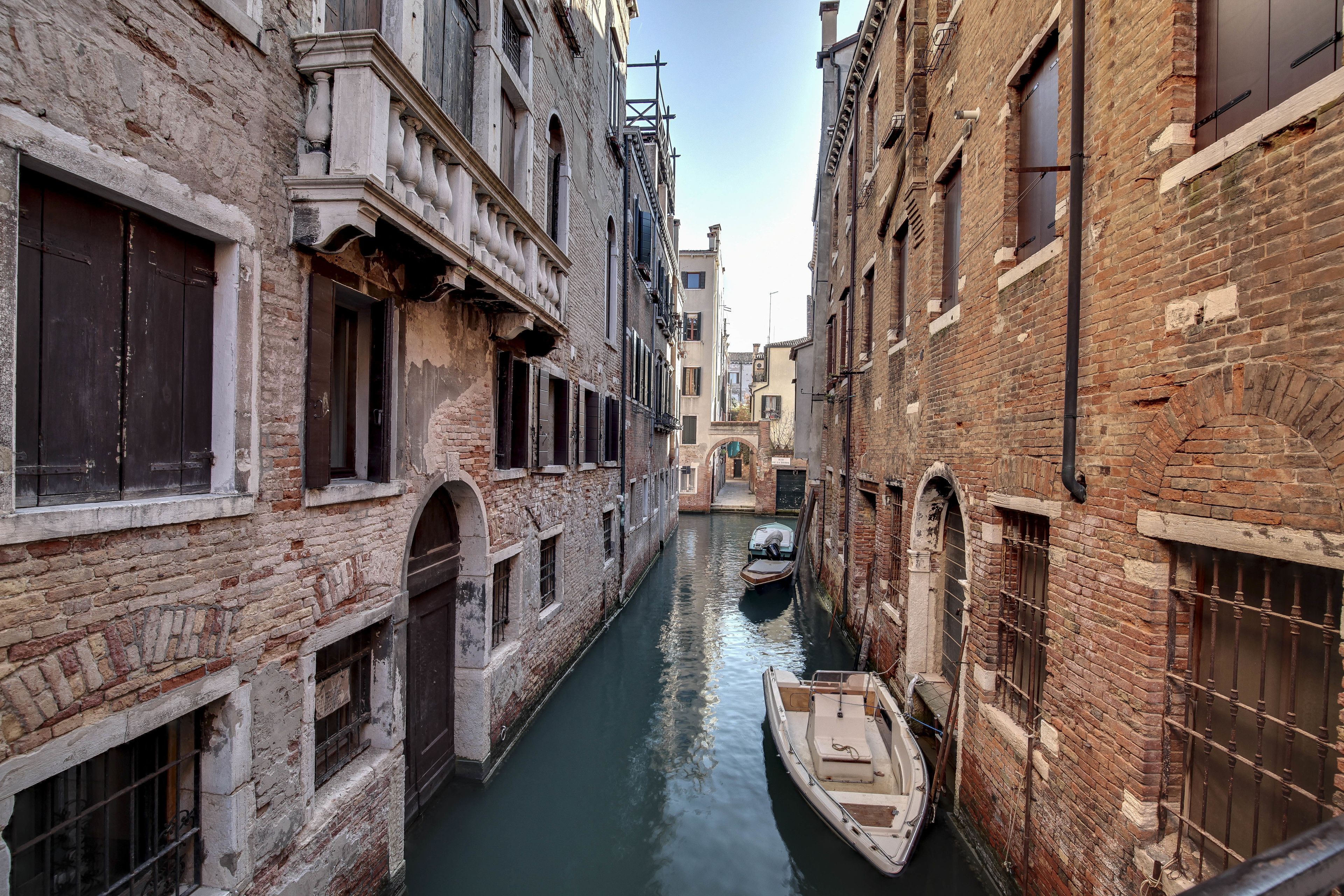 A narrow canal flanked by historic buildings with arched windows and brick facades.