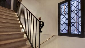 A staircase with a black metal railing and a window with a grid pattern. - Canal View Suite in Rialto by Wonderful Italy (Venice)