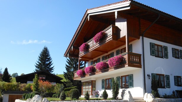 A multi-story building with wooden balconies, stone walls, and a clear sky.