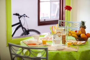 Uma mesa de café da manhã com uma fruteira, croissants e uma cafeteira.