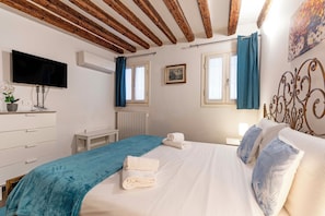 A bedroom with a bed, a TV, a radiator, and a window with curtains. - San Giacomo Pied-A-Terre House by Wonderful Italy (Venice)