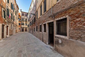A narrow cobblestone street flanked by historic buildings with traditional architecture, including visible doors and windows. - San Giacomo Pied-A-Terre House by Wonderful Italy (Venice)