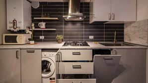 A compact kitchen with a built-in microwave, a gas stove, a washing machine, and a sink.