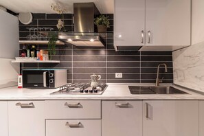 A modern kitchen with a gas stove, microwave, and stainless steel cabinets. - San Giacomo Pied-A-Terre House by Wonderful Italy (Venice)