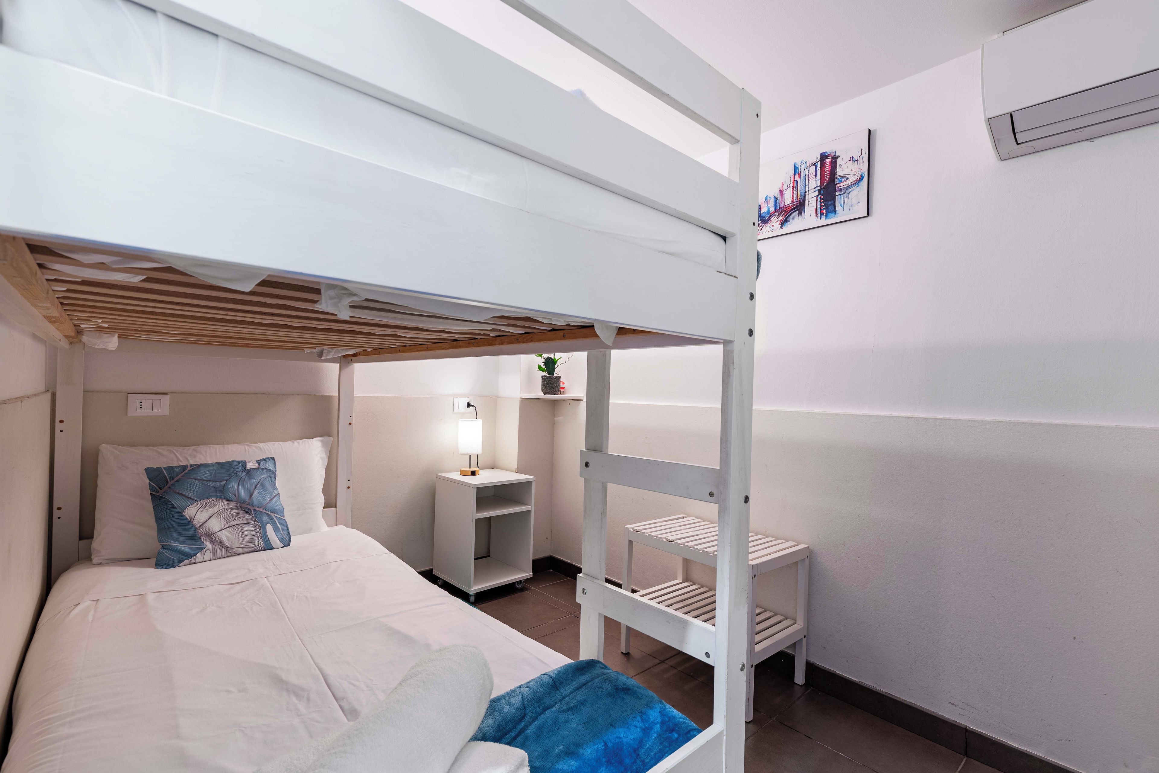 Habitación con literas, escritorio y estante.