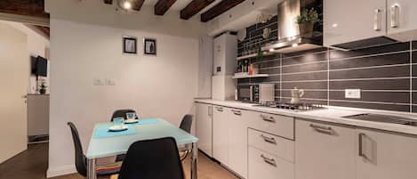 A modern kitchen with white cabinetry, a gas stove, and a black tiled backsplash.