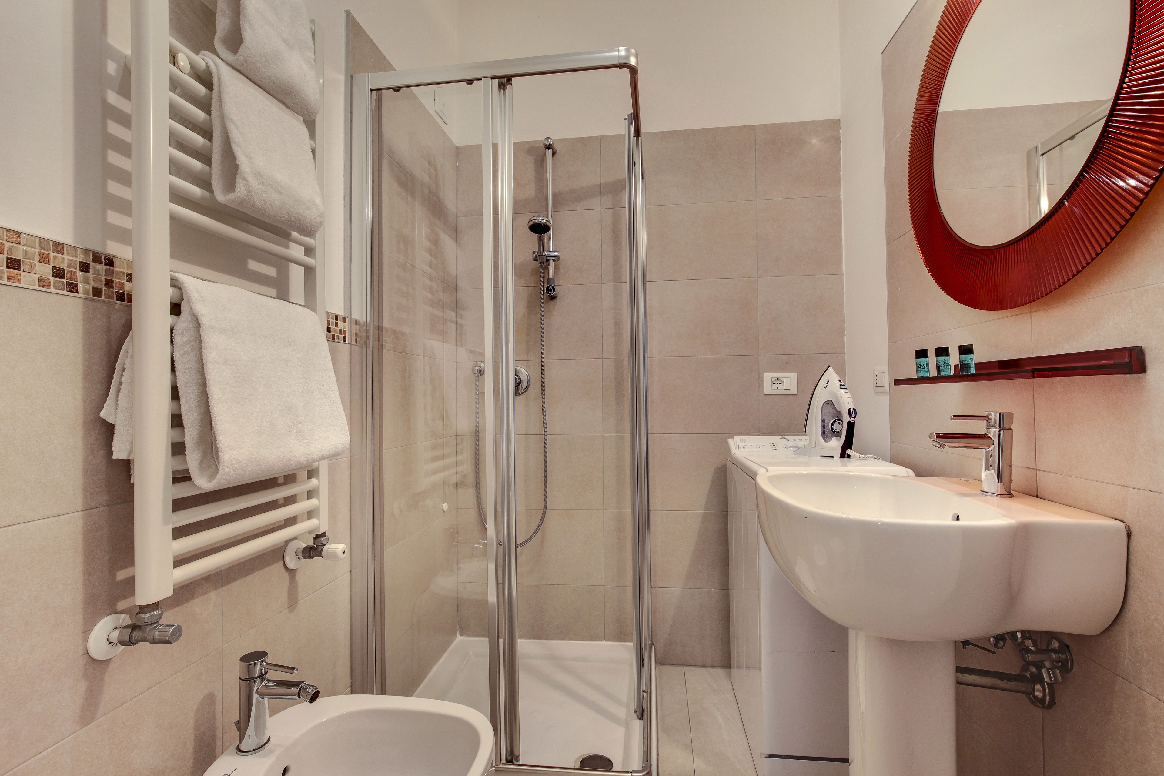 A modern bathroom with a glass-enclosed shower, a white sink, and a towel rack with neatly folded towels.