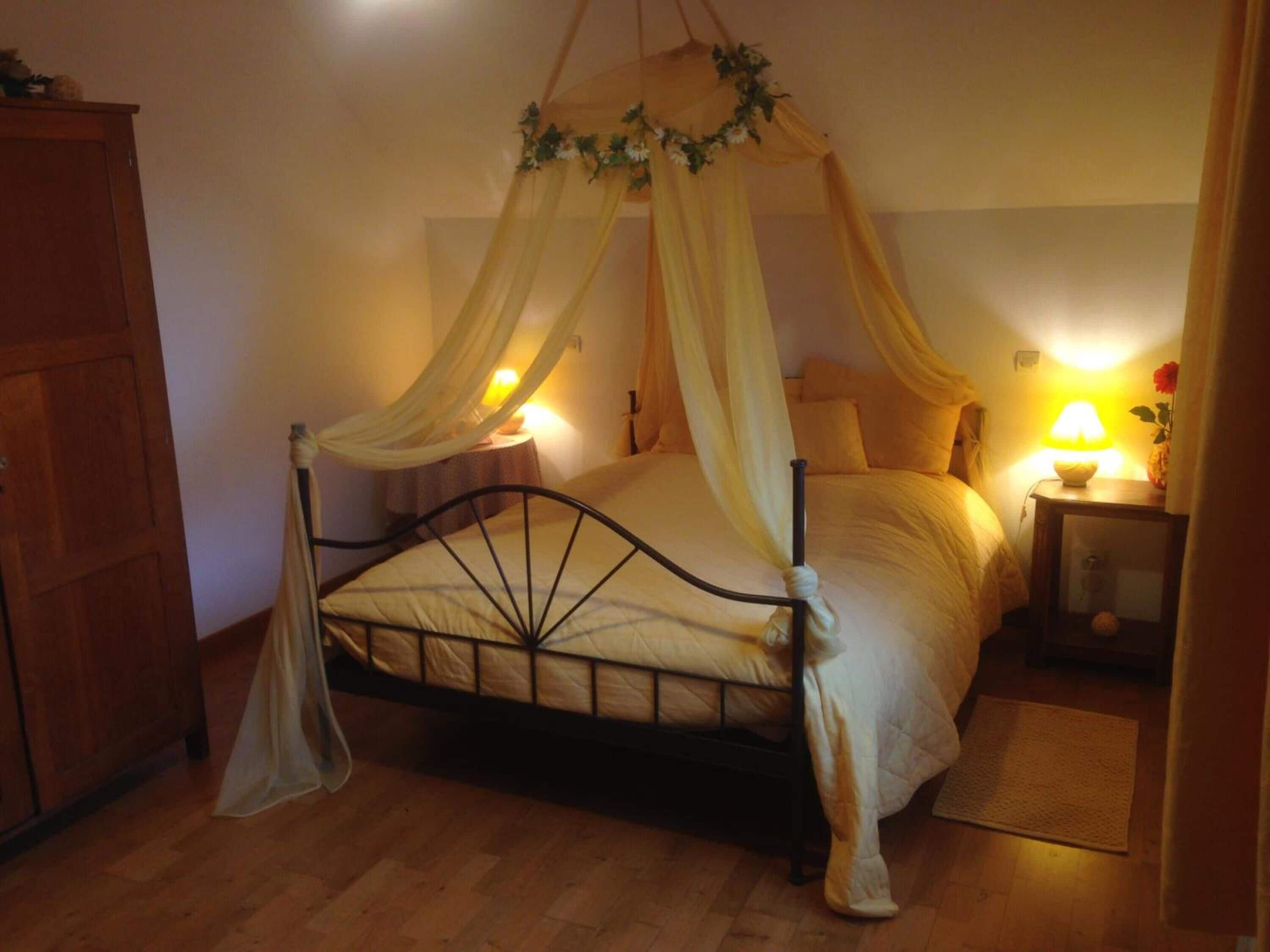 Una camera da letto con un letto a baldacchino, un armadio in legno e un comodino con una lampada.