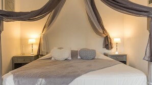 A bedroom with a canopy bed, two bedside tables with lamps, and a wall-mounted artwork. - Le Moulin de la Côte - Chambre d'Hôtes (Saint-Vigor)