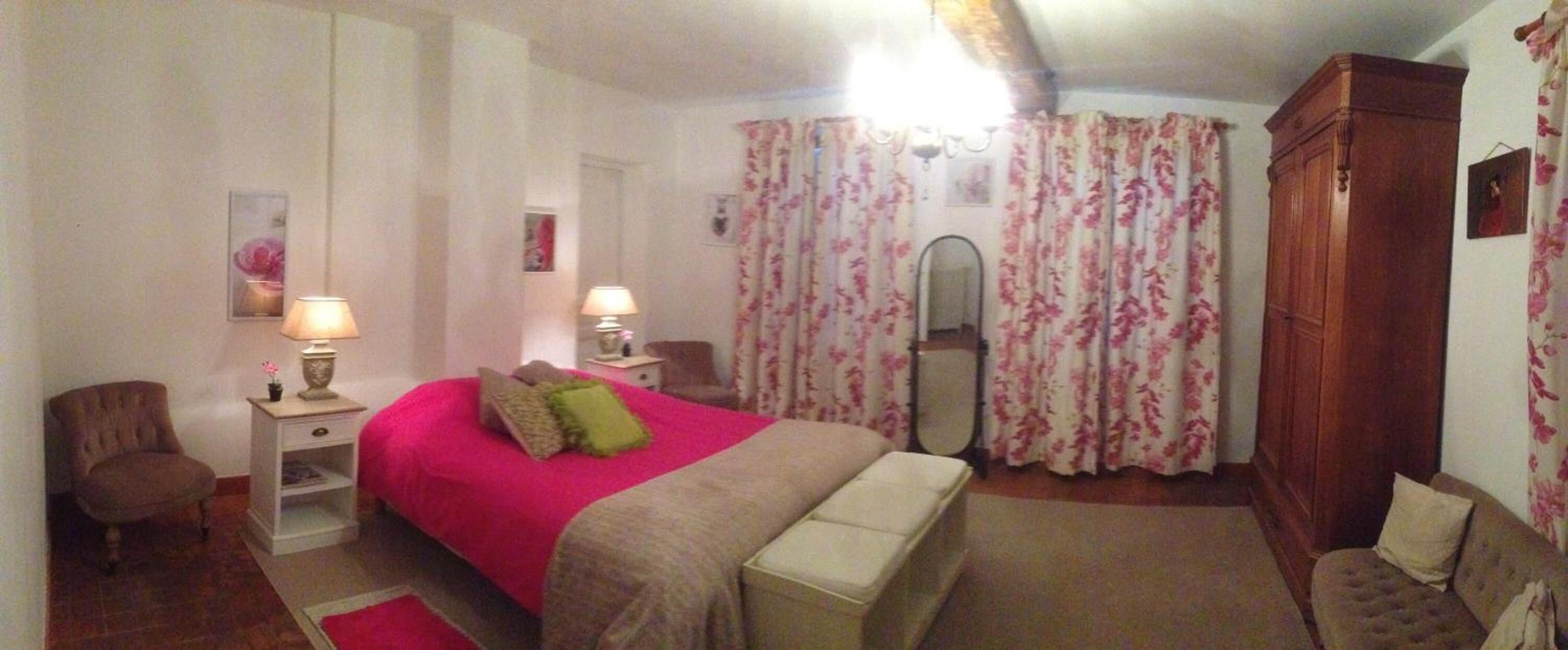A bedroom with a bed, bedside tables, a chair, a wardrobe, and floral curtains.
