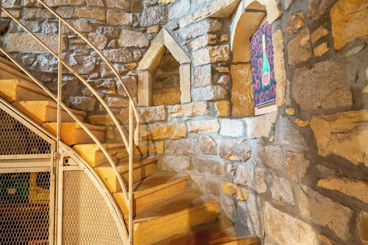 A stone staircase with a metal railing and a decorative stained glass window.
