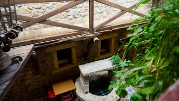 A rustic stone structure with a wooden roof, a small window, and a stone bench.
