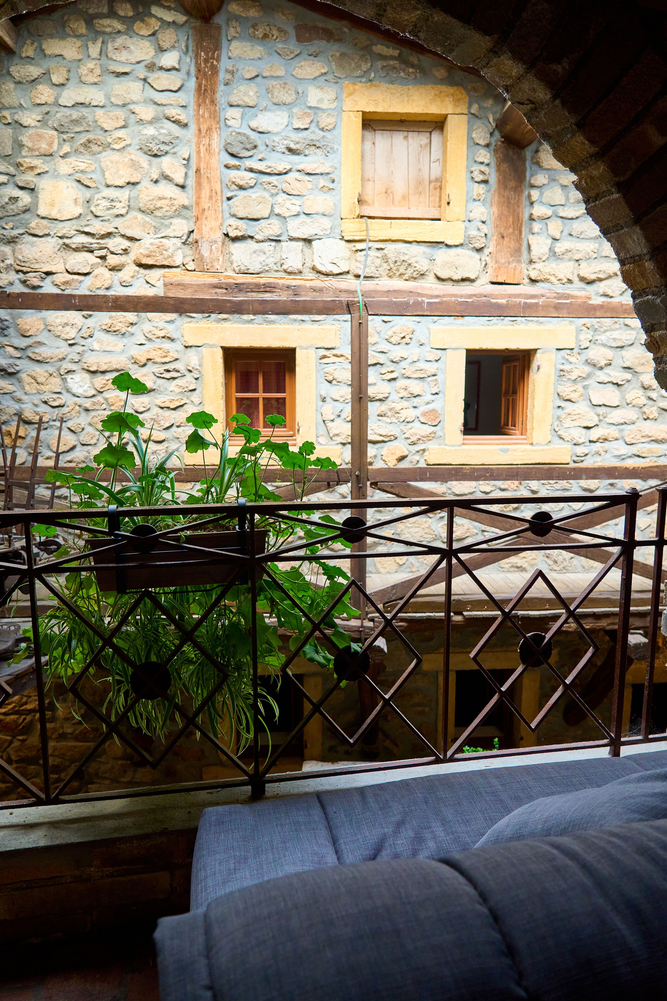 A stone building with two windows and a balcony with a metal railing.