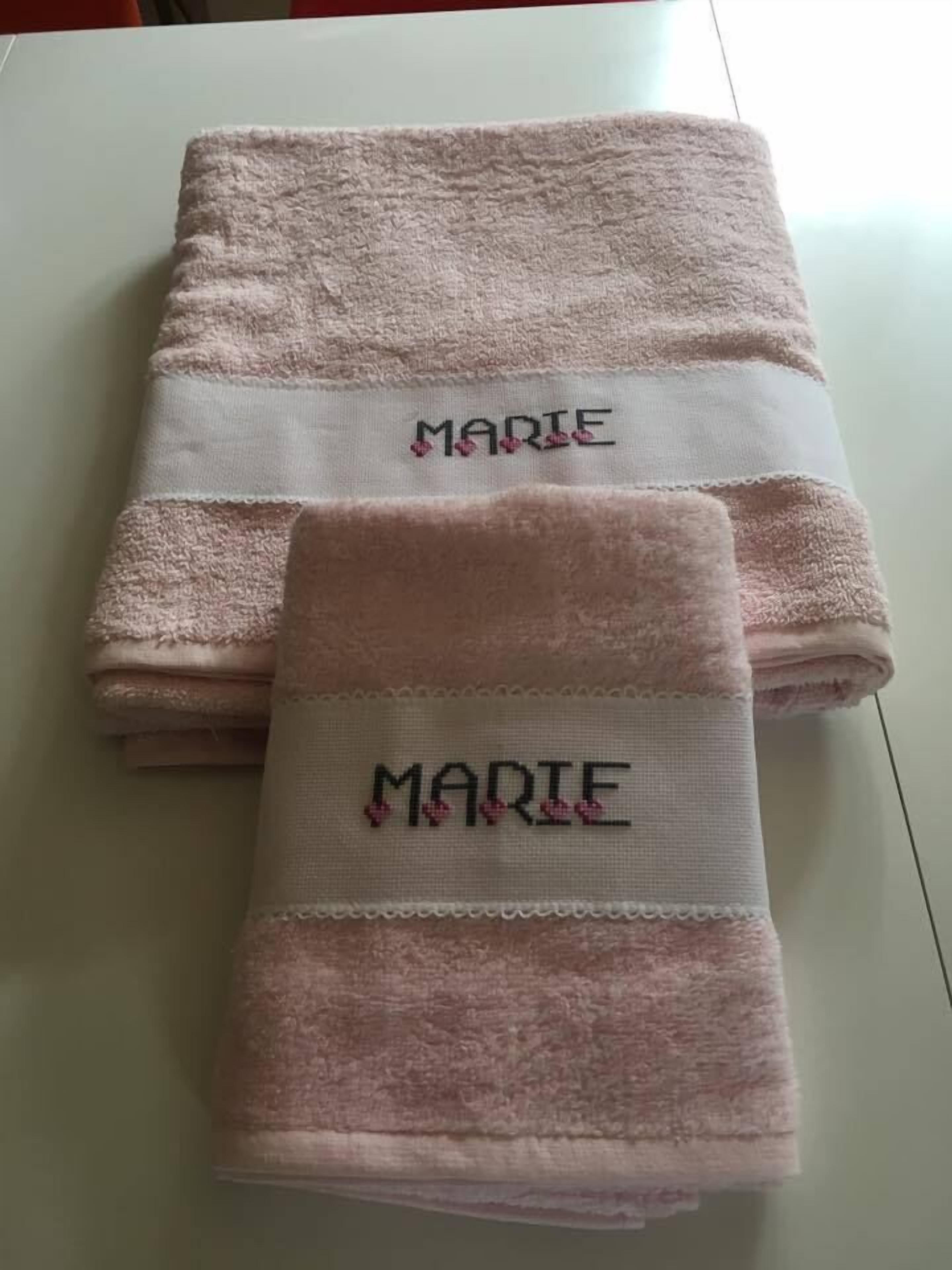 Two folded towels with the name "MARIE" embroidered on them, placed on a white surface.