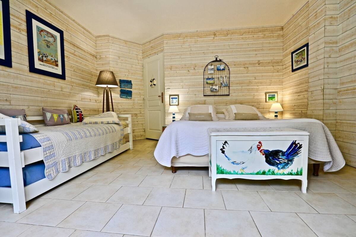 Un dormitorio acogedor con dos camas, paredes de madera y una jaula de pájaros en el techo.