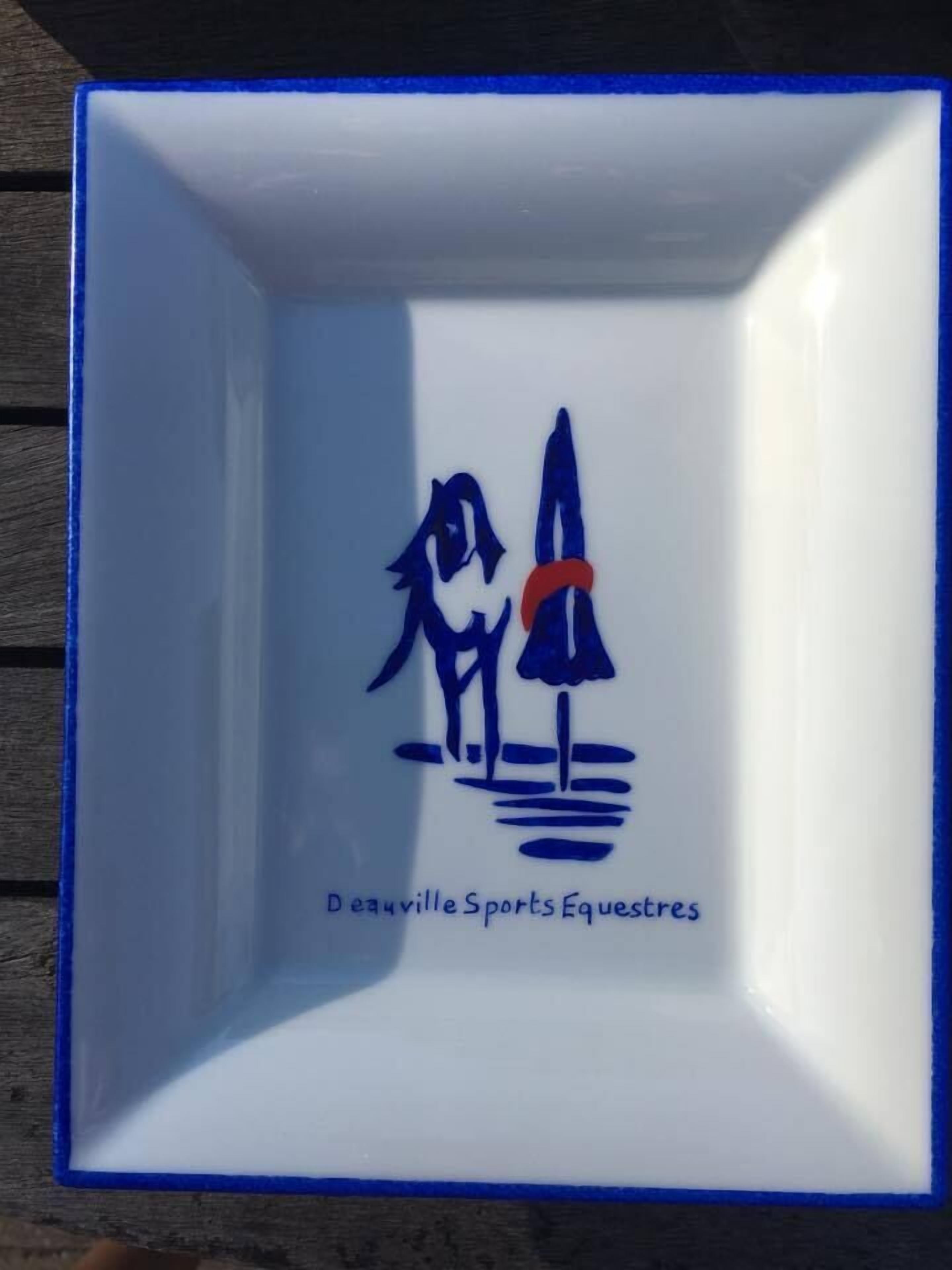 Un bol en céramique blanche, orné d’un bord bleu et d’une silhouette représentant une personne tenant un parapluie.