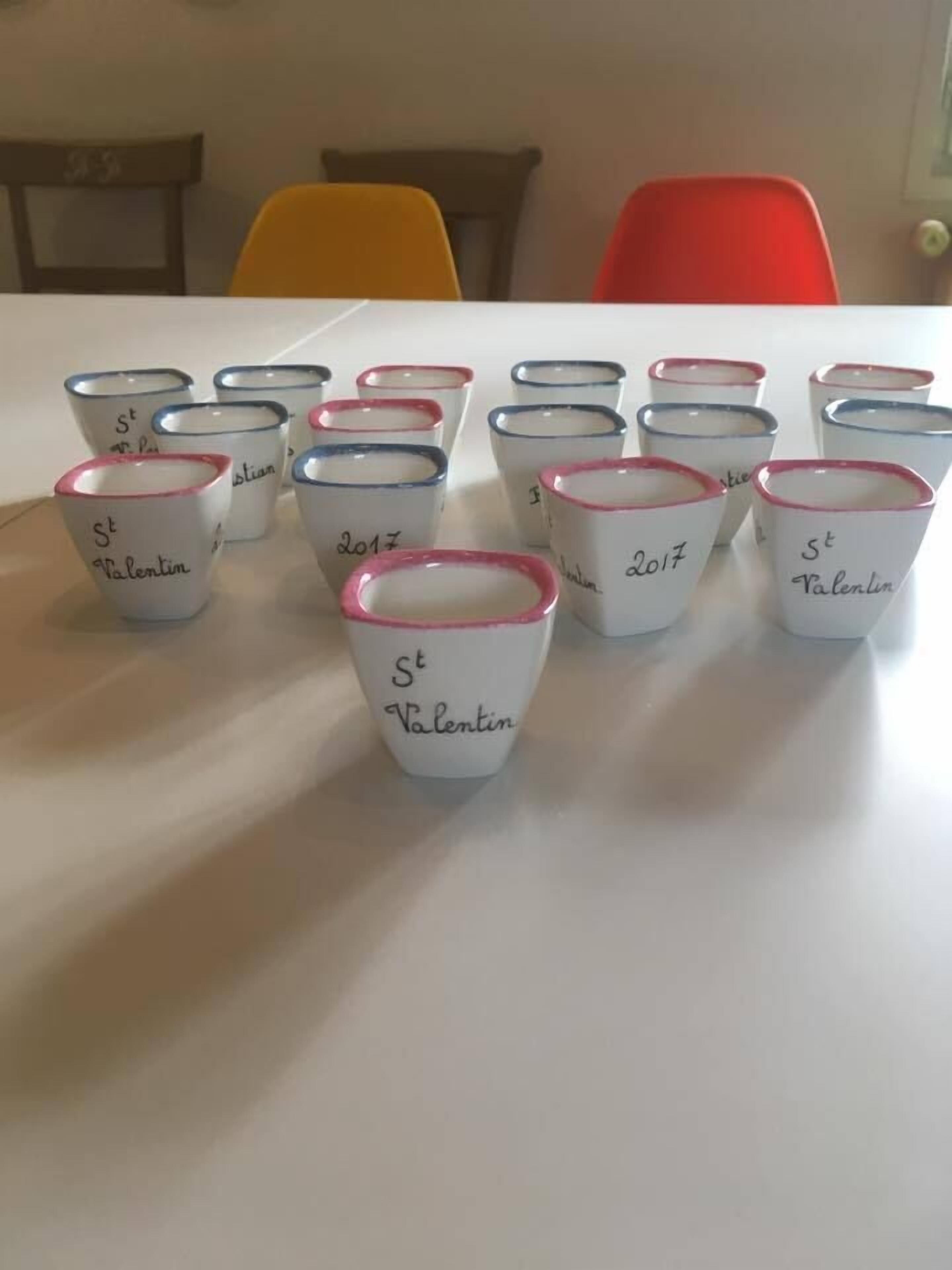 Una mesa con varias tazas blancas de borde rojo y el texto "St Valentin" y "2017".