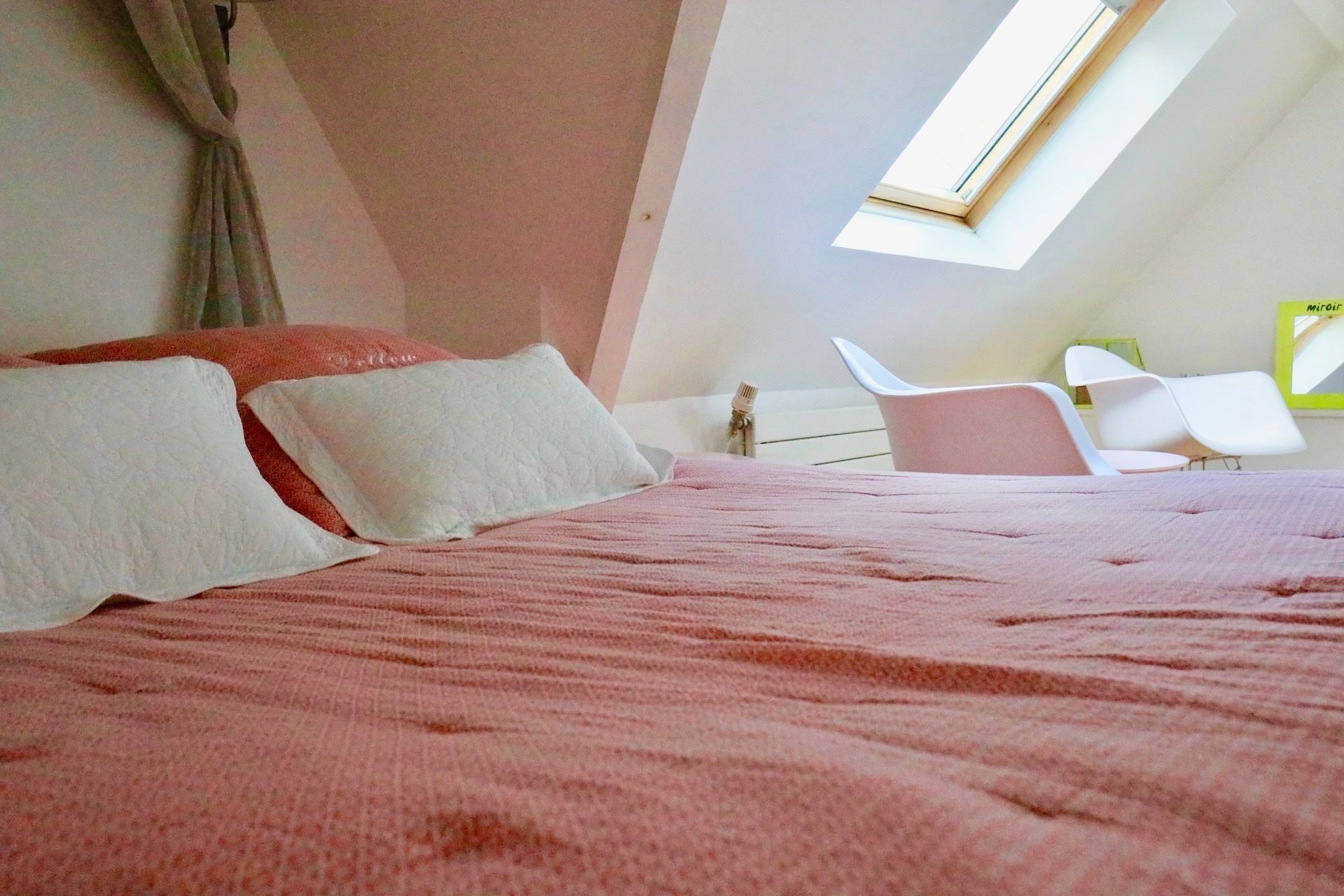 Un dormitorio con cama, almohadas, una ventana y una silla.