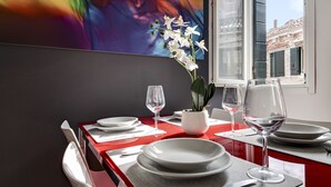 A dining table set with white plates, wine glasses, and a potted orchid. - Charming Castello Apartments by Wonderful Italy (Venice)