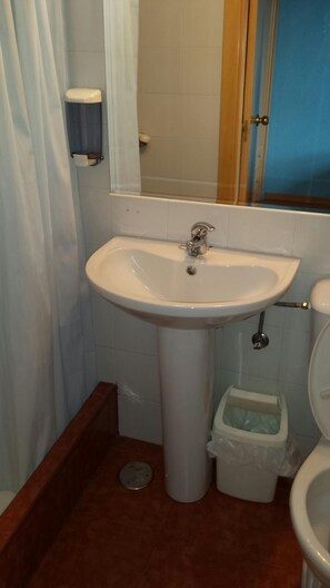 A bathroom with a white sink, a toilet, and a trash bin. - Residencia Universitaria Cum Laude (Salamanca)