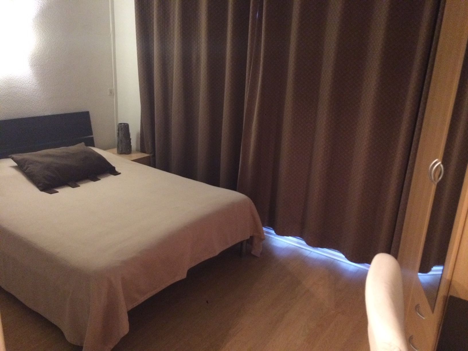 Et hotelværelse med en seng, et natbord, en lampe og en dør.