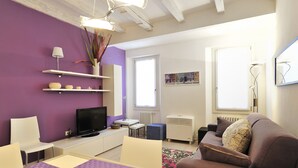 A modern living room with a television, sofa, and a dining area with a table and chairs. - Venetian Dream in Biennale Area by Wonderful Italy (Venice)