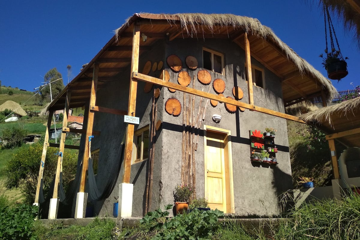 Ein rustikales Haus mit einem Reetdach, Holzbalken und einer Holztür.