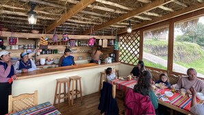 Un interior rústico de madera con techo de paja, una zona de bar y un espacio comedor con mesas y sillas de madera.