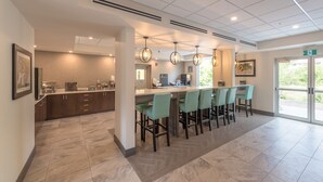 A modern bar area with a long counter, multiple bar stools, and pendant lighting. - Coast Oliver Hotel (Oliver)