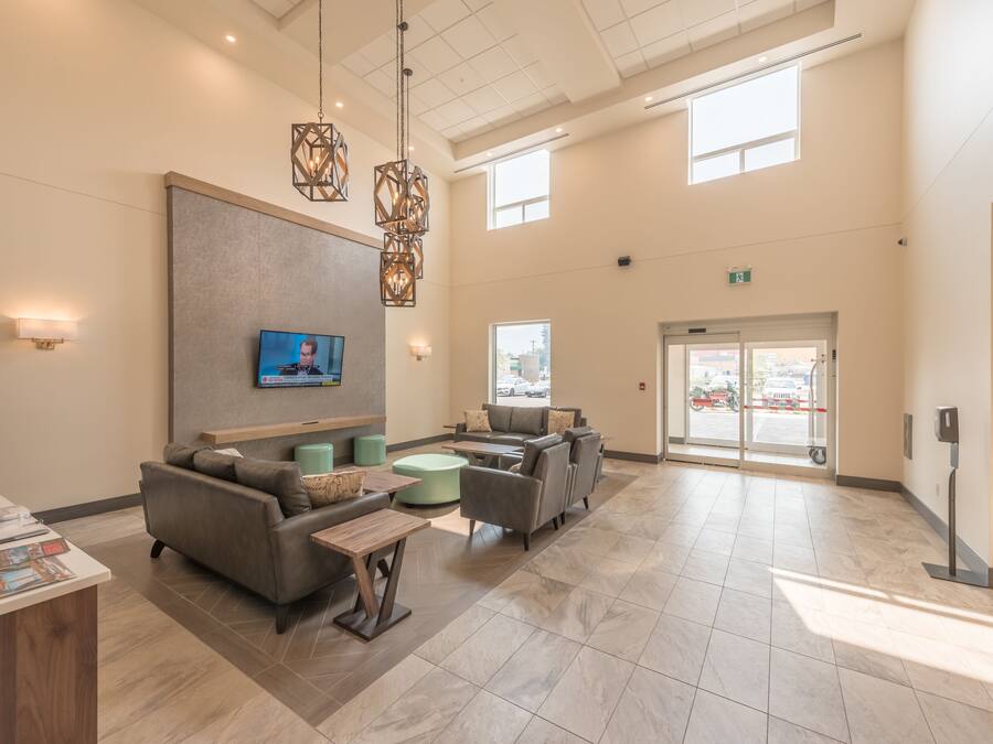 A spacious lobby with a reception desk, comfortable seating, a television, and a large window providing natural light.