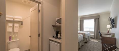 Habitación de hotel con inodoro, refrigerador pequeño, microondas, escritorio, silla y cama.