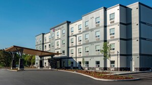 A multi-story hotel with a modern design, featuring a covered entrance area and a parking lot. - Coast Oliver Hotel (Oliver)