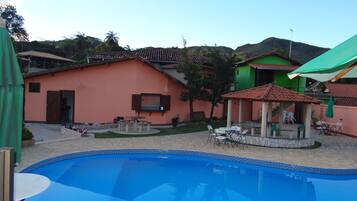 A swimming pool with a tiled edge, surrounded by a patio area with outdoor furniture.