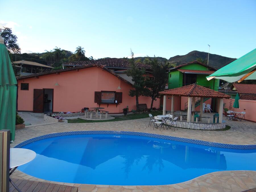 A swimming pool with a tiled edge, surrounded by a patio area with outdoor furniture.