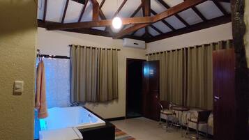 Una habitación de hotel con cama, escritorio, silla, televisión y ventilador de techo.