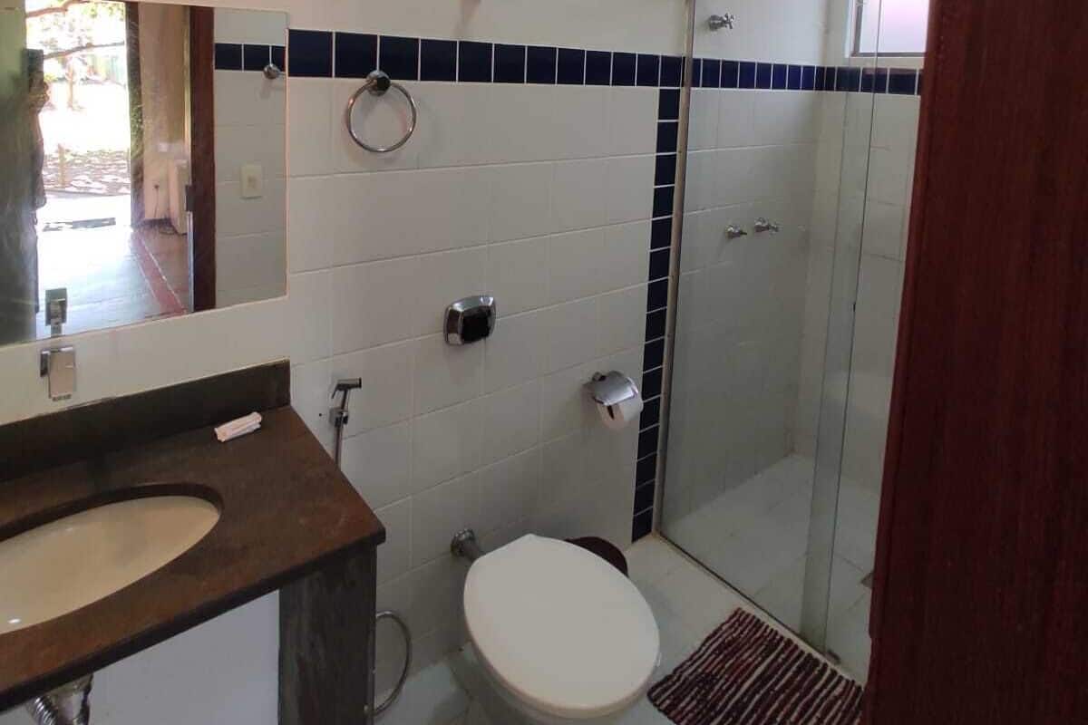 A bathroom with a white toilet, a sink, a mirror, and a shower area.